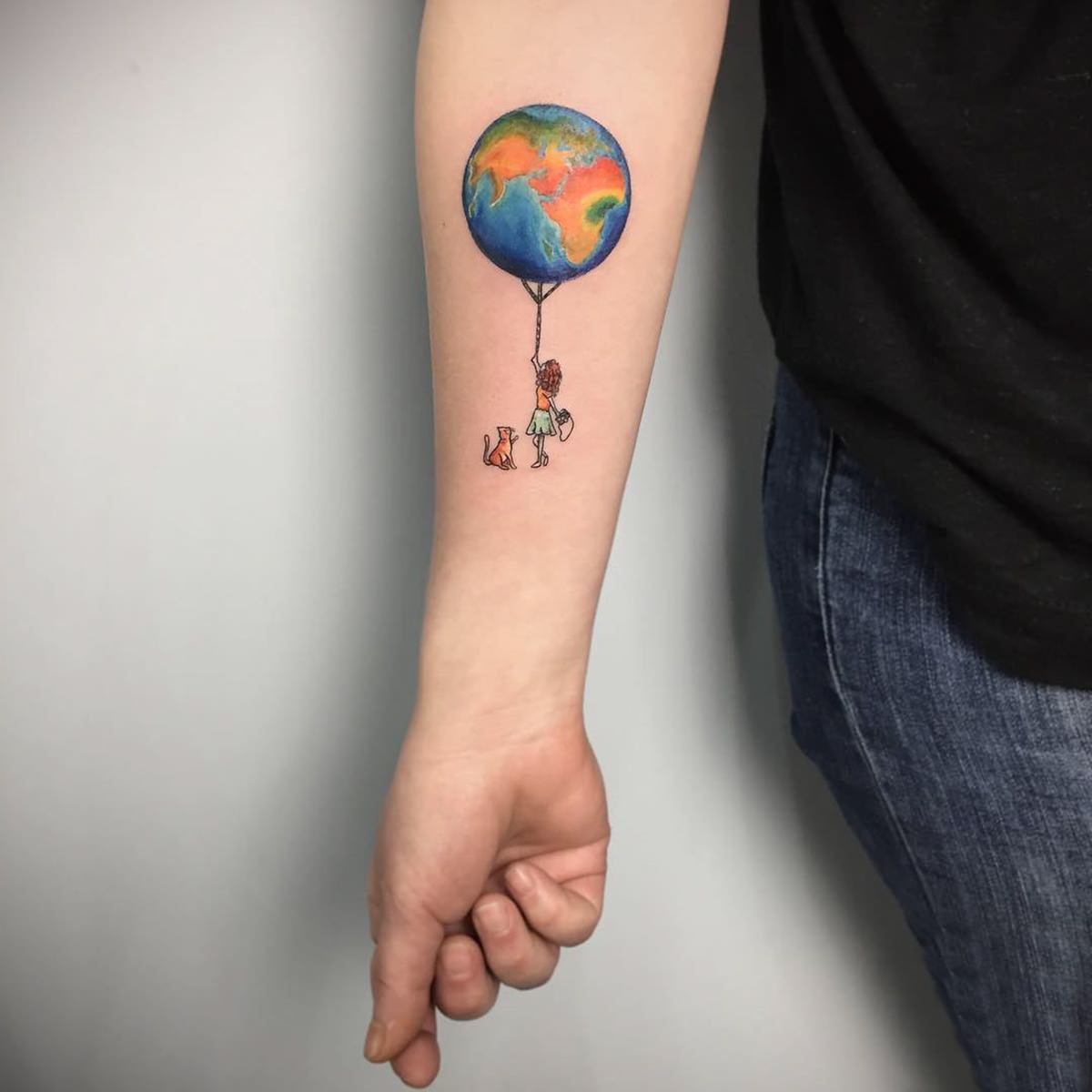 Tattoo de garotinha segurando balão em formato de planeta Terra