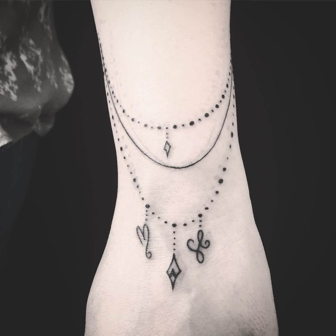 Tatuagem feminina delicada simulando joias no pulso