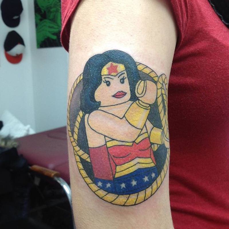 Lego da mulher maravilha tatuado no braço