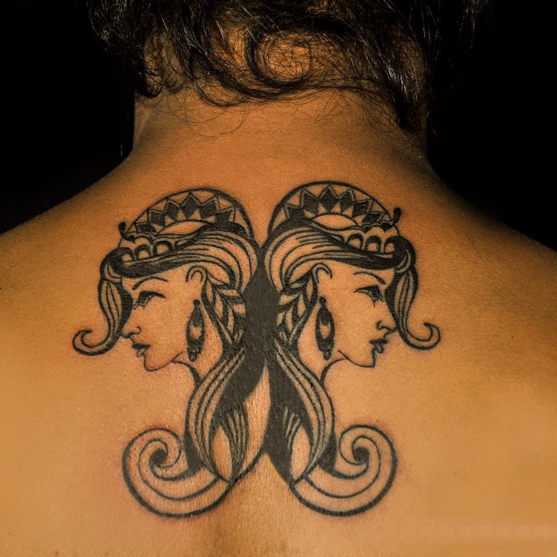 Tatuagem feminina nas costas do signo de gêmeos