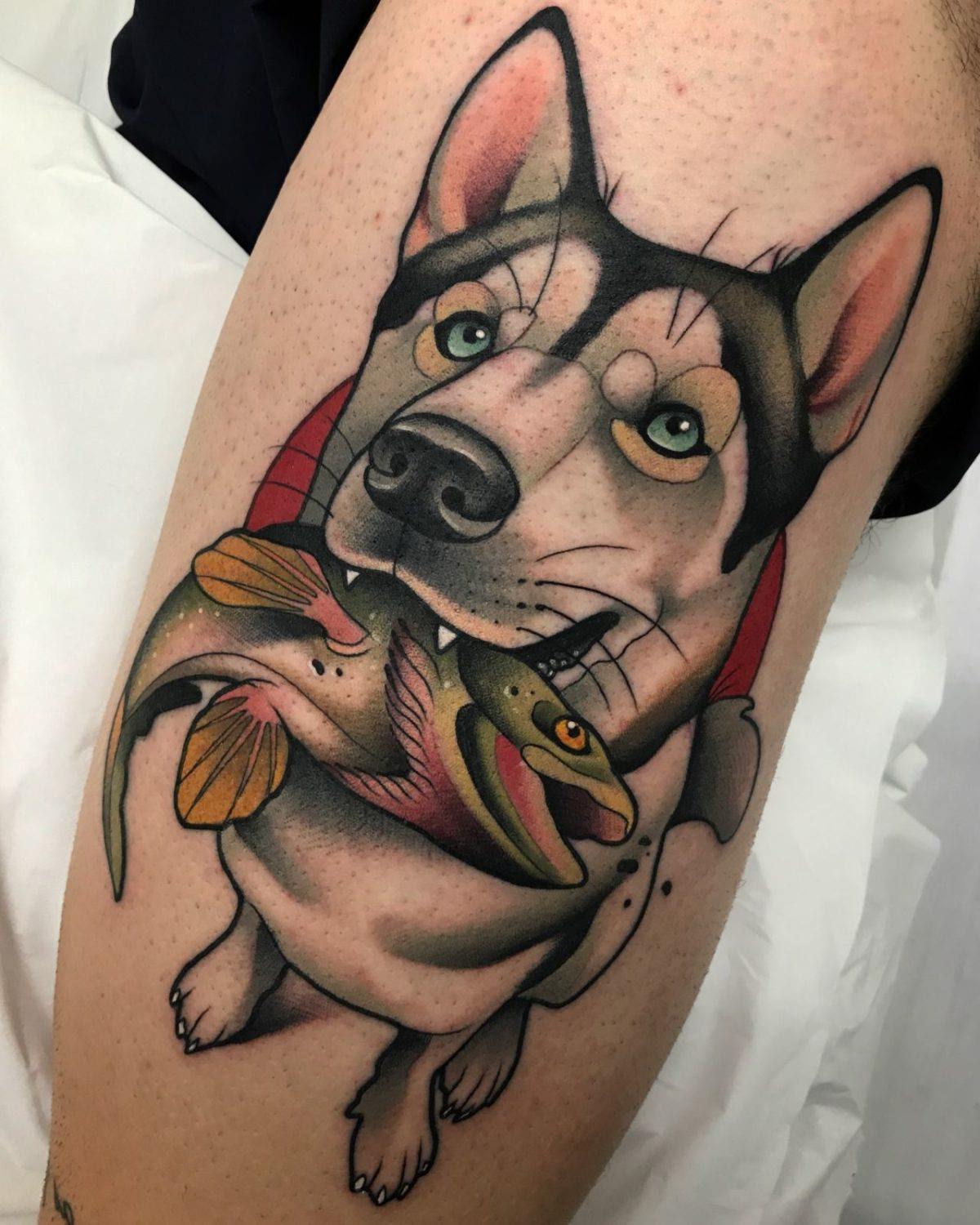 Tatuagem colorida de um cão segurando o peixe com a boca