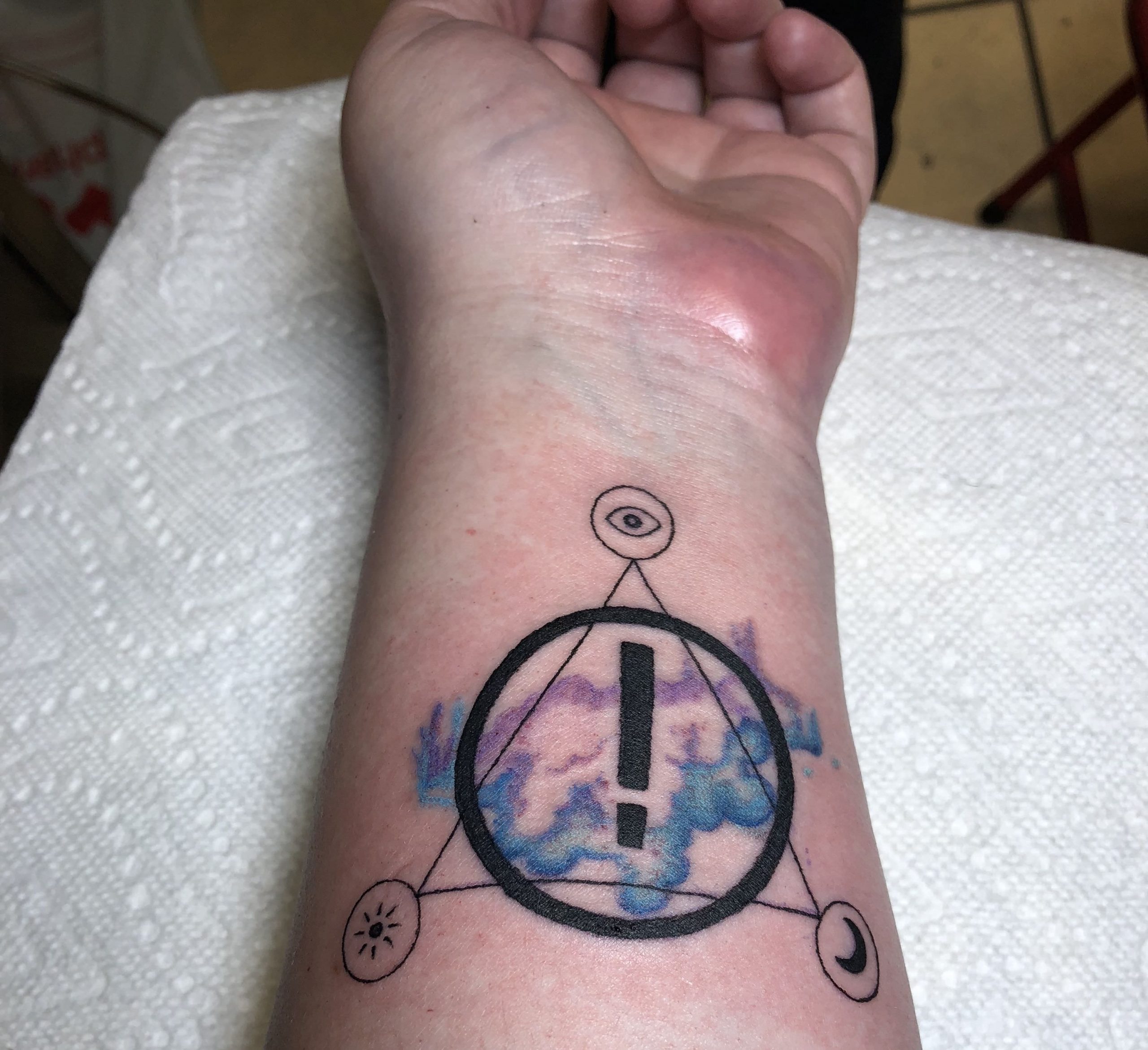 Simbolo EMO tatuado no braço
